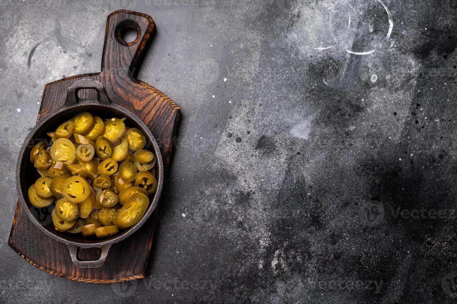Pickled Jalapeno, Marinated Green Mexican pepper Slices in a skillet. black background. top view photo