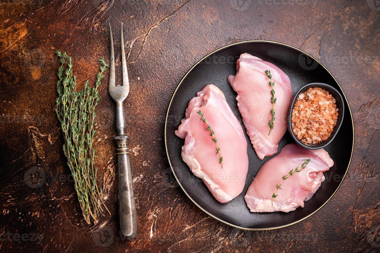 Raw Chicken thigh fillet meat, Skinless boneless poultry meat on a plate. brown background. top view photo