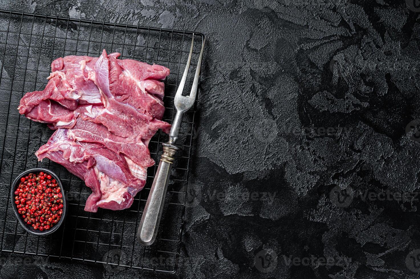 Raw Turkey sliced fillet meat ready for cooking. Black background. Top view. Space for text photo