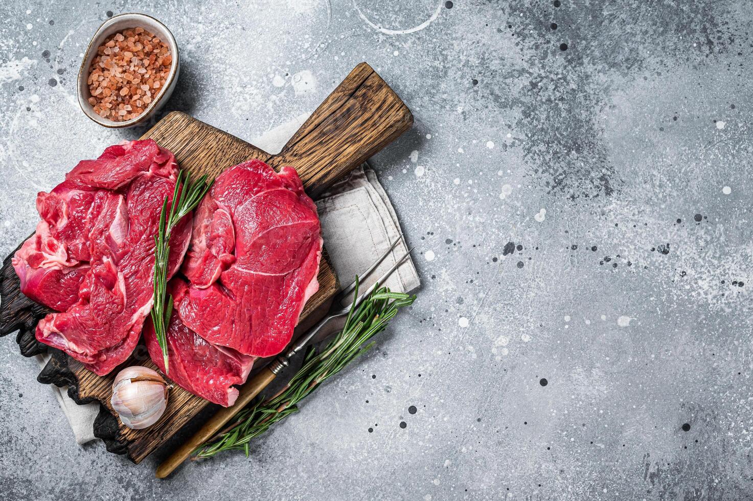 Uncooked Raw Lamb chop leg steaks on cutting board. Gray background. Top view. Copy space photo