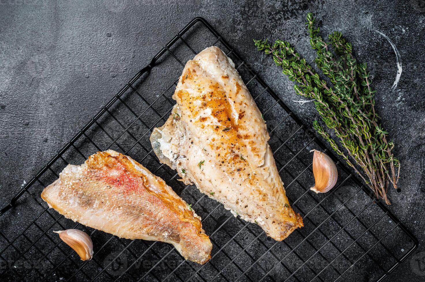 Grilled sea red perch fillet, Snapper fish on a rack. Black background. Top view photo