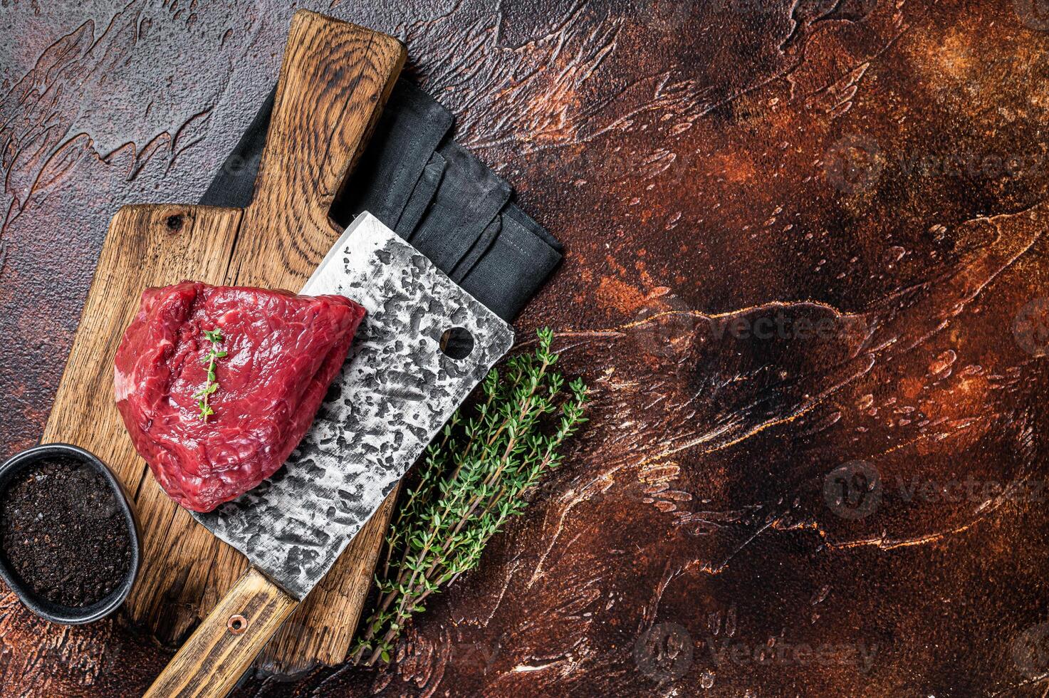 Raw rump steak on a butcher cutting board. Dark background. Top view. Copy space photo