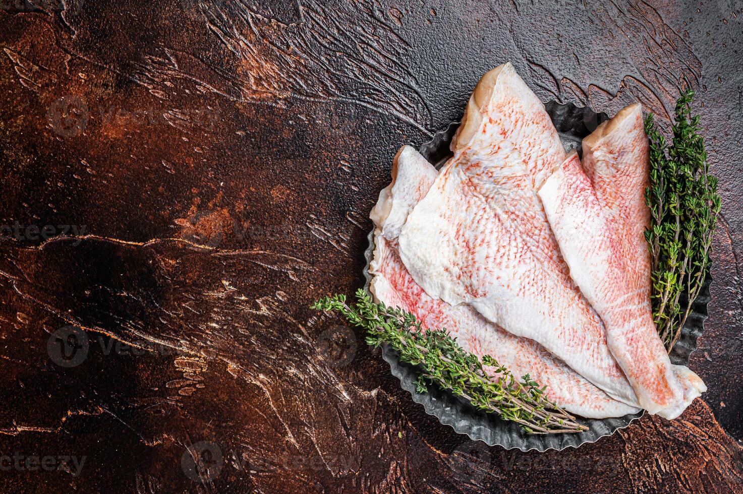 Raw ocean red perch fillet, Snapper fish with herbs. Dark background. Top view. Copy space photo