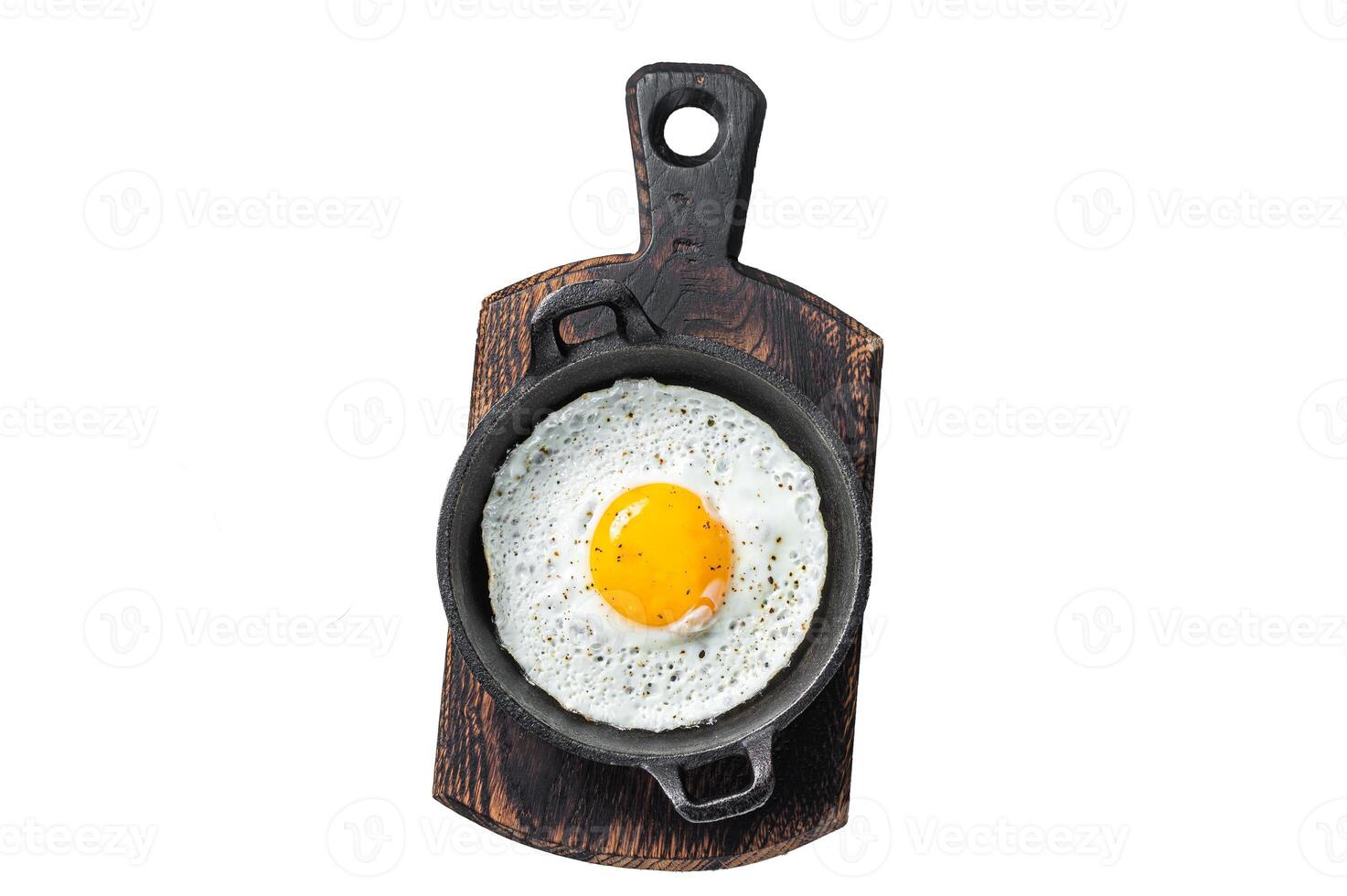 Salted and spiced fried egg in pan with tomatoes, thyme and bacon. Isolated, white background. photo