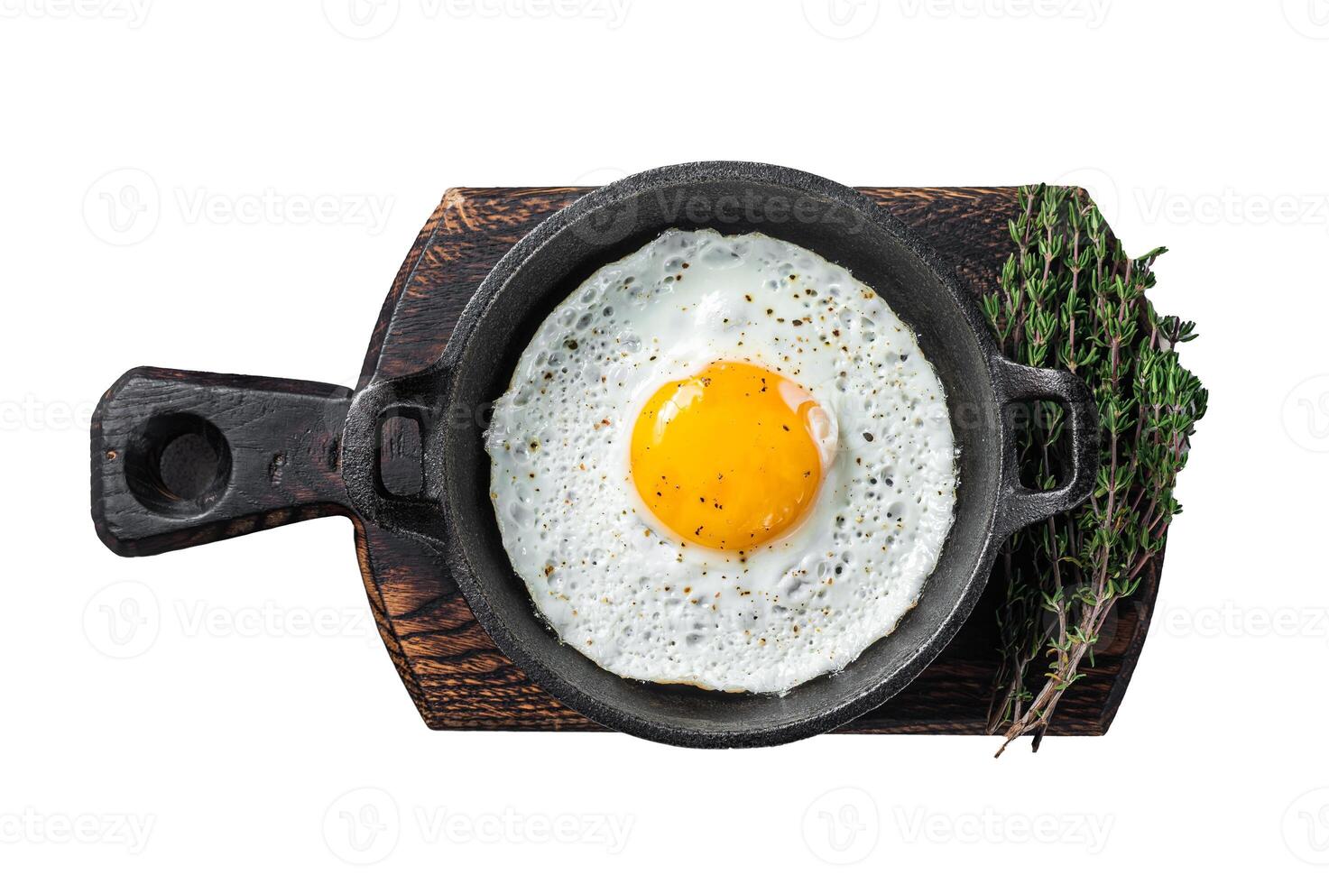 Salted and spiced fried egg in pan with tomatoes, thyme and bacon. Isolated on white background photo