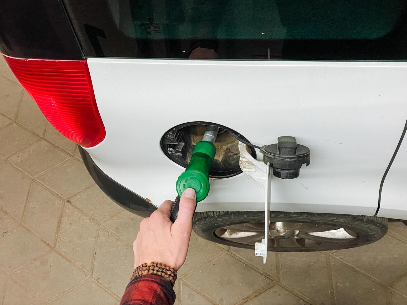 A person is currently engaged in the important action of pumping gas into a whitecolored automobile, ensuring that it is properly refueled and ready for its next journey or travel plans photo