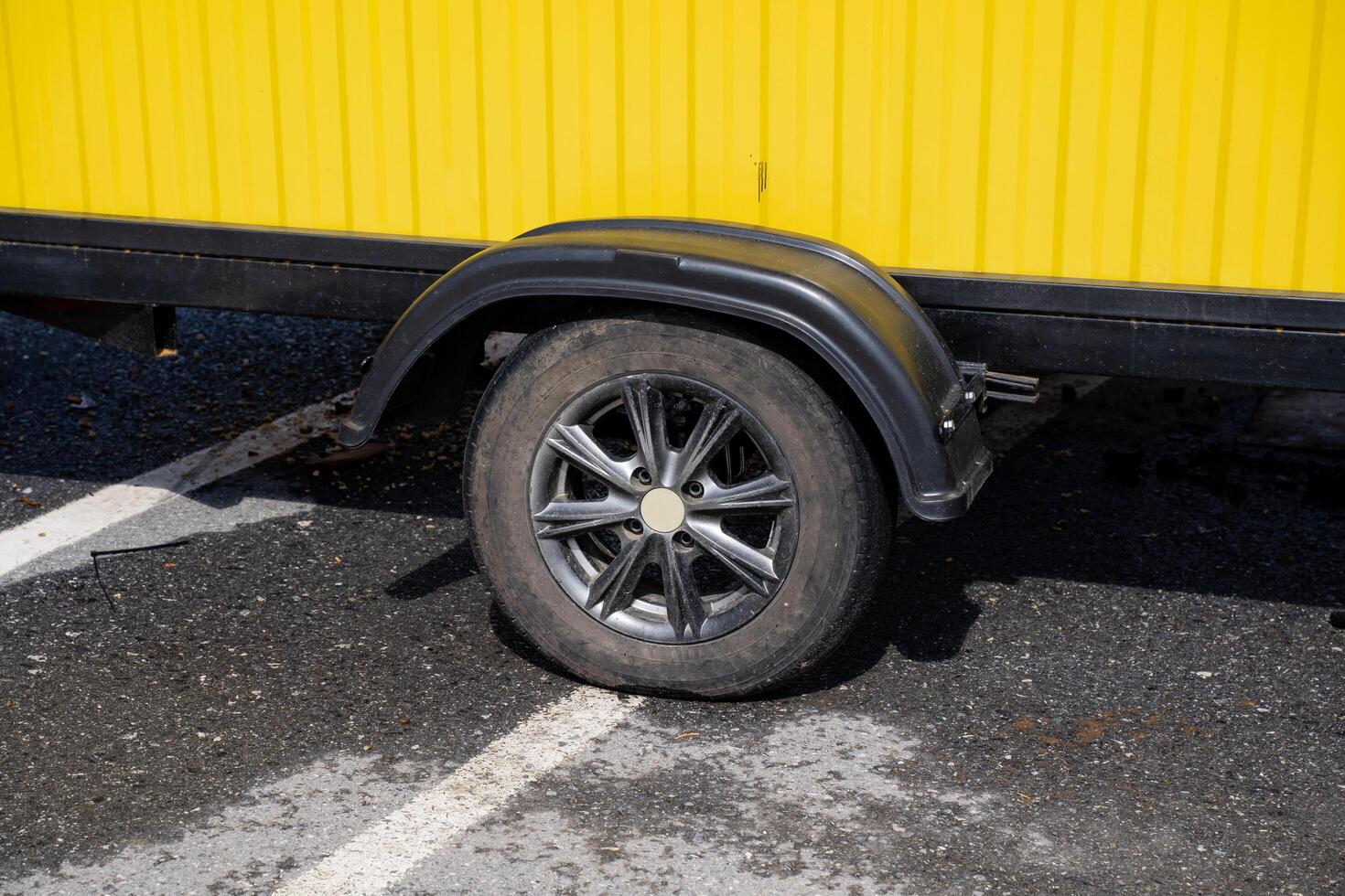 In a parking lot, there is a yellow trailer parked, reflecting sunlight and standing out among other vehicles, creating a vibrant scene that catches the eye of passersby photo