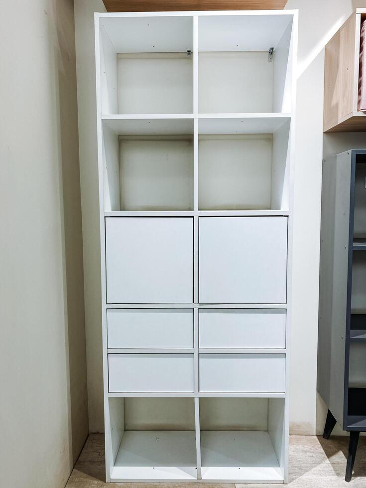 In a cozy room, there stands a lovely white shelf, which features both drawers and doors, offering ample storage space, enhancing the overall decor, and serving multiple diverse functions photo