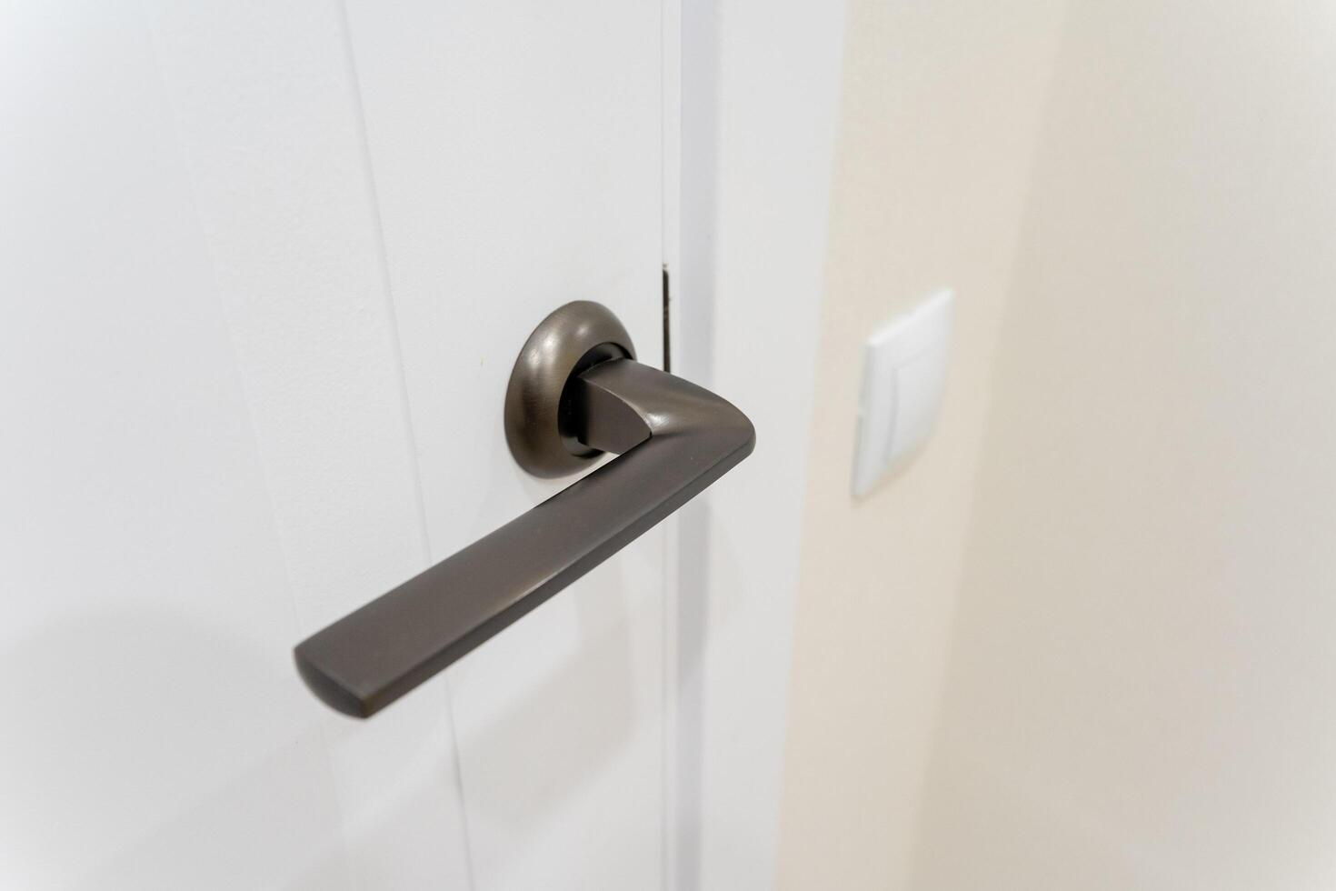 This detailed closeup image presents a beautifully crafted door handle mounted on an immaculate white door, emphasizing the exquisite intricacies and thoughtful design elements involved photo