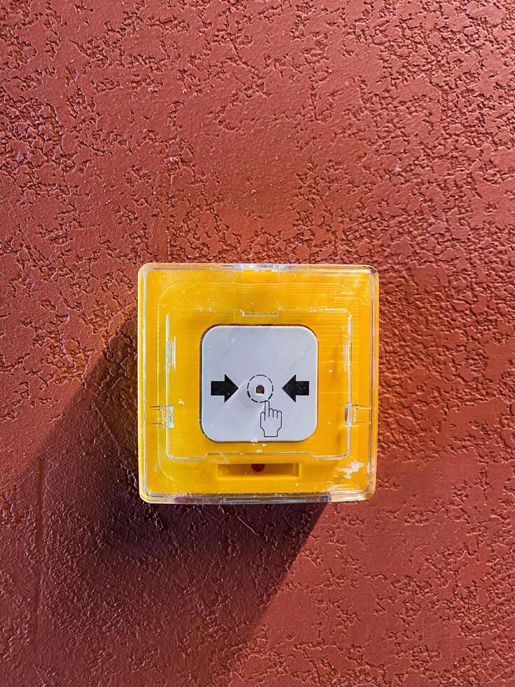 A vibrant yellow emergency call button is prominently displayed on a textured wall, ensuring safe communication during urgent situations photo
