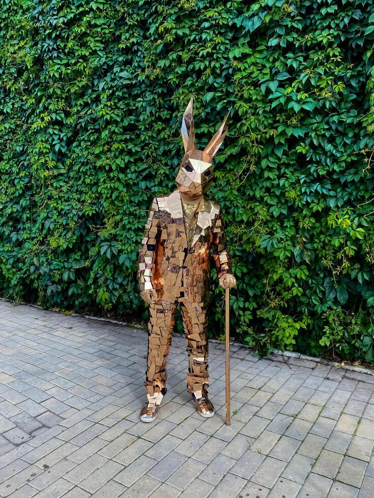 A man in a rabbit costume stands on the sidewalk with a cane photo