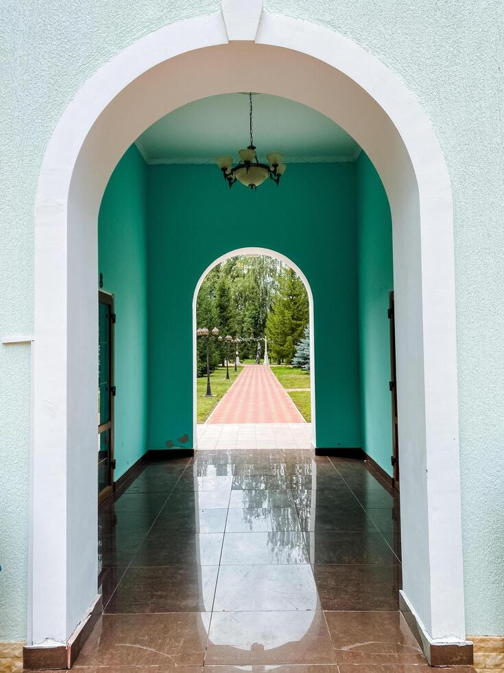 An elegantly designed archway connects a stunning hallway to a serene park, creating a seamless transition that enhances the overall ambiance and experience of the space photo