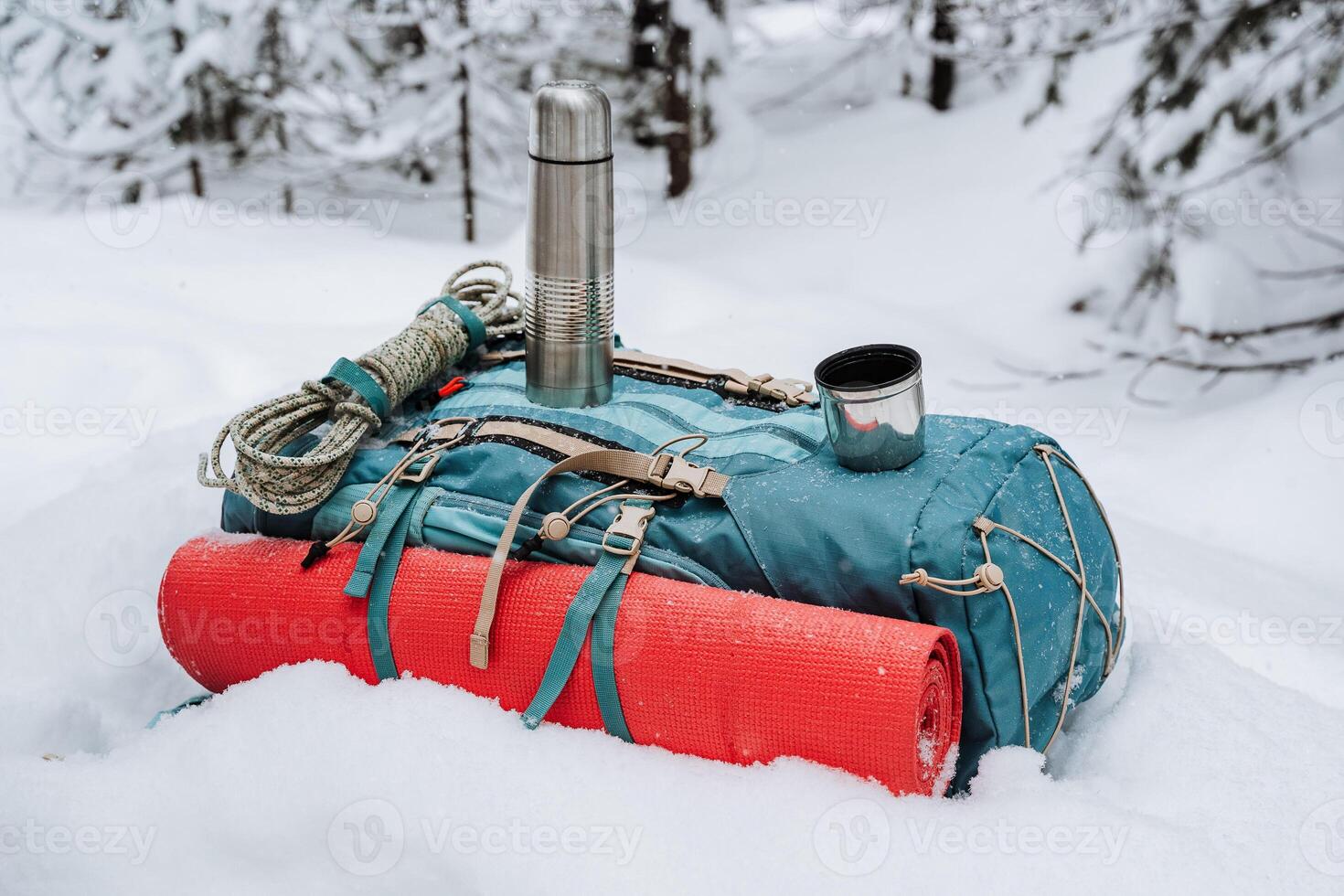 A backpack with a thermos, a coffee cup and a red mat photo