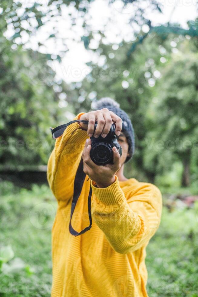 Portrait of man holding a camera over a forest photo