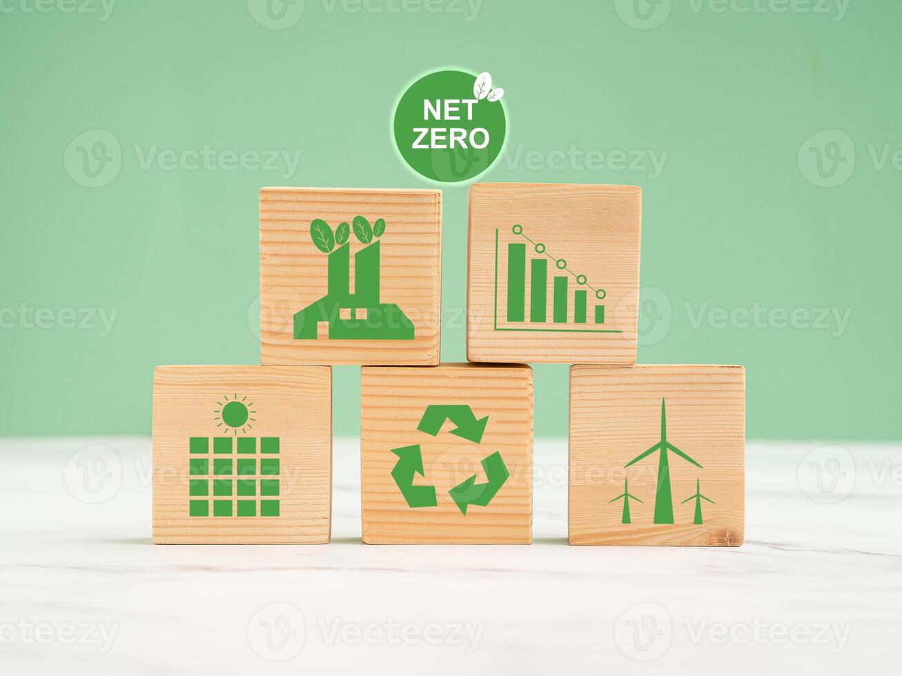 Net-zero emissions in 2050. World Earth day concept. Wooden cubes with eco-friendly icons over a marble floor against a green background photo