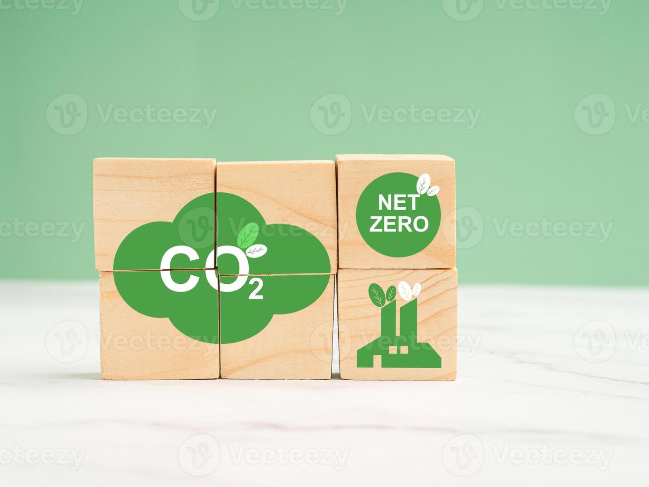 Net-zero emissions in 2050. World Earth day concept. Wooden cubes with eco-friendly icons over a marble floor against a green background photo