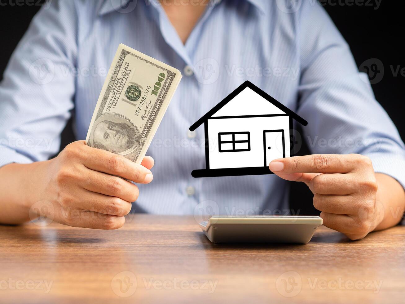 A businessman's hands holding a US dollars banknote and a mini paper house while sitting in the office photo