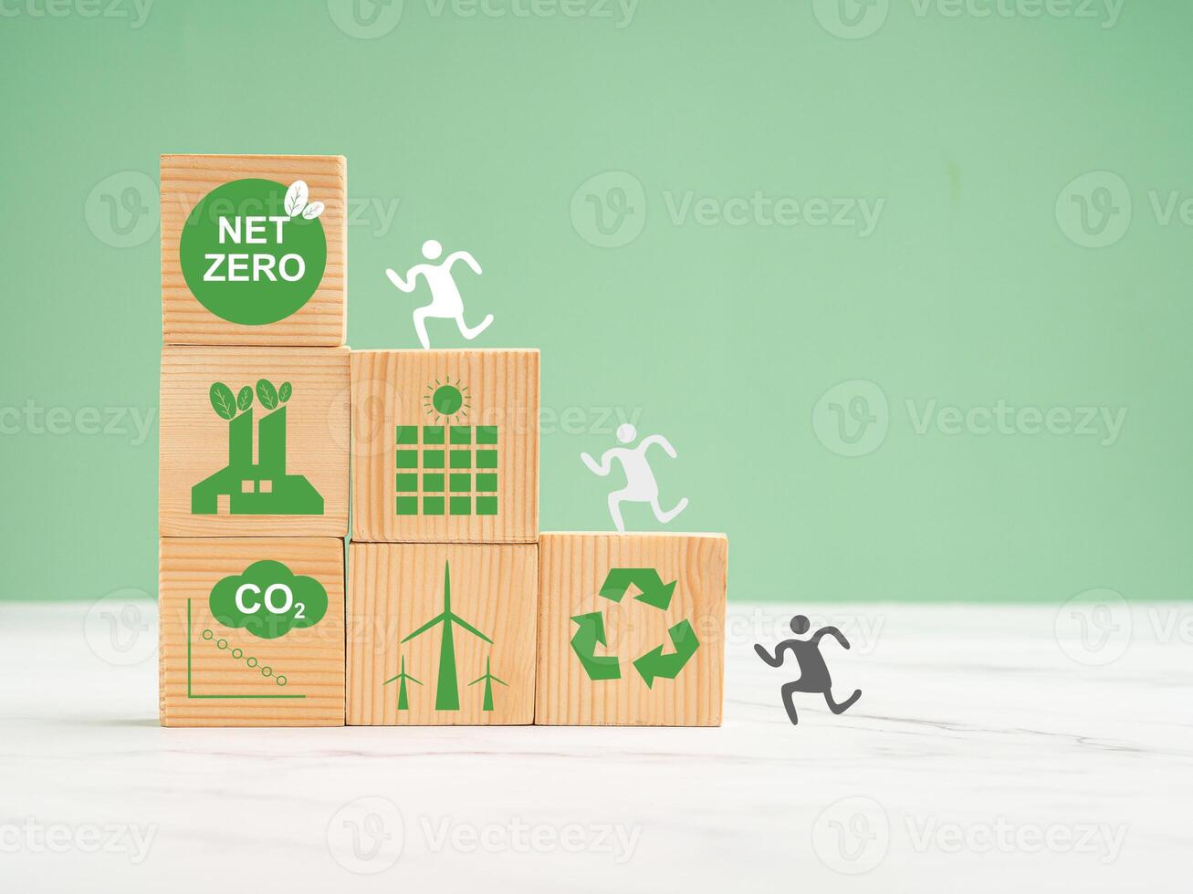Net-zero emissions in 2050. World Earth day concept. Wooden cubes with eco-friendly icons over a marble floor against a green background photo