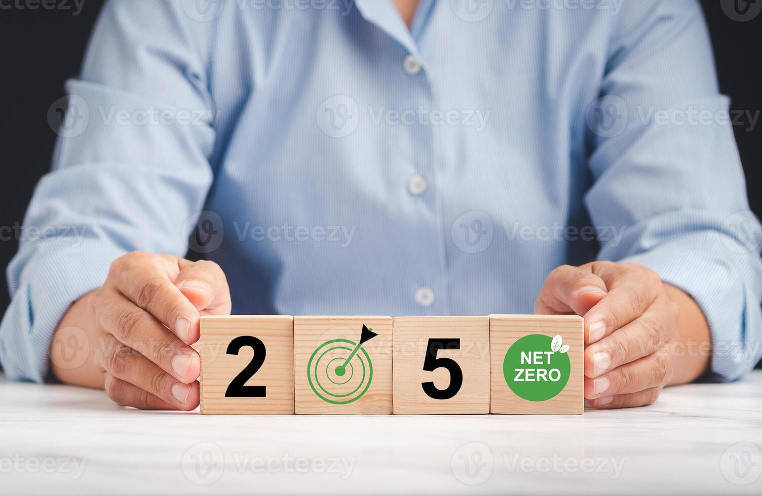 Net-zero greenhouse gas emissions in 2050 target. Climate-neutral long-term strategy. Hands protect wooden cubes with green icons while sitting in the office photo