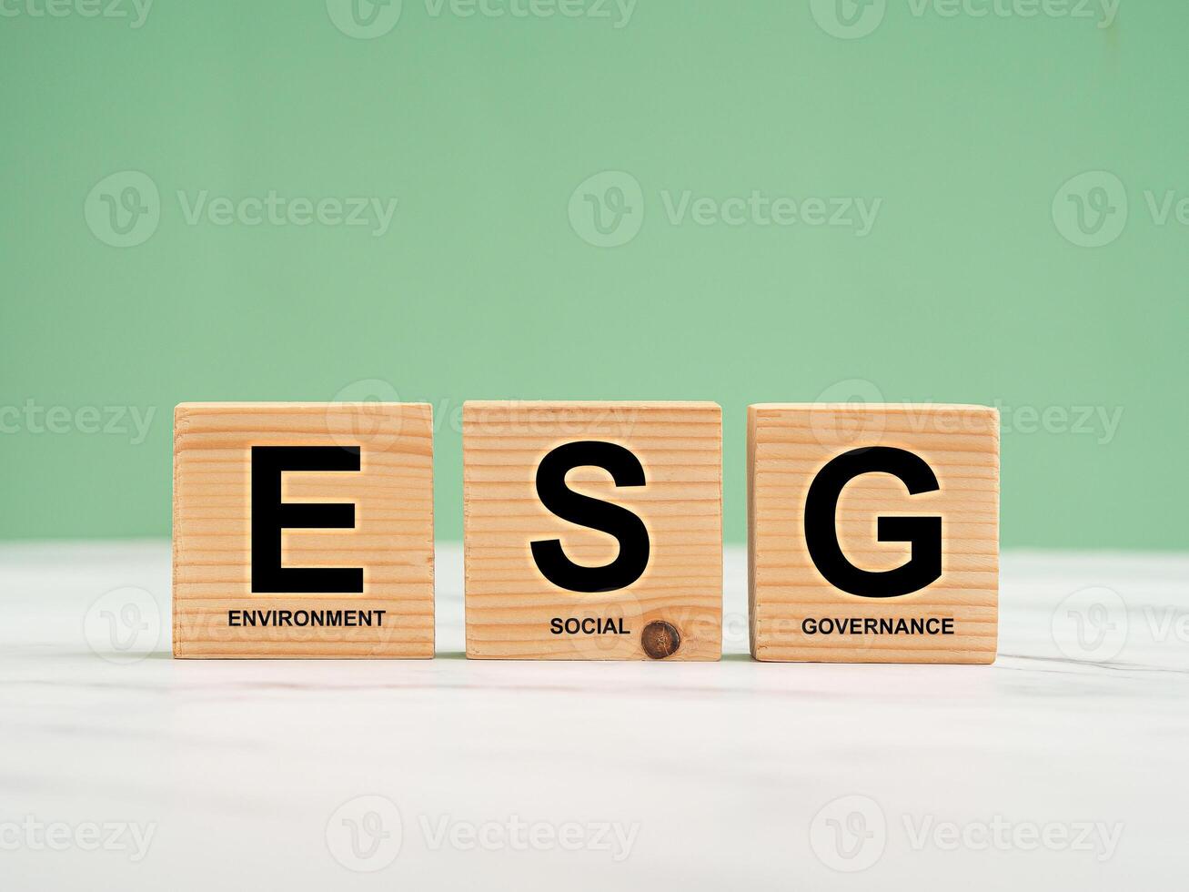 ESG concept of environmental, social, and governance. Wooden cubes with the letters ESG over a marble floor with a green background photo