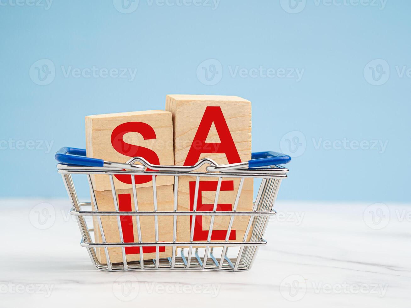 A miniature shopping trolley and wooden blocks with the word SALE on a blue background photo