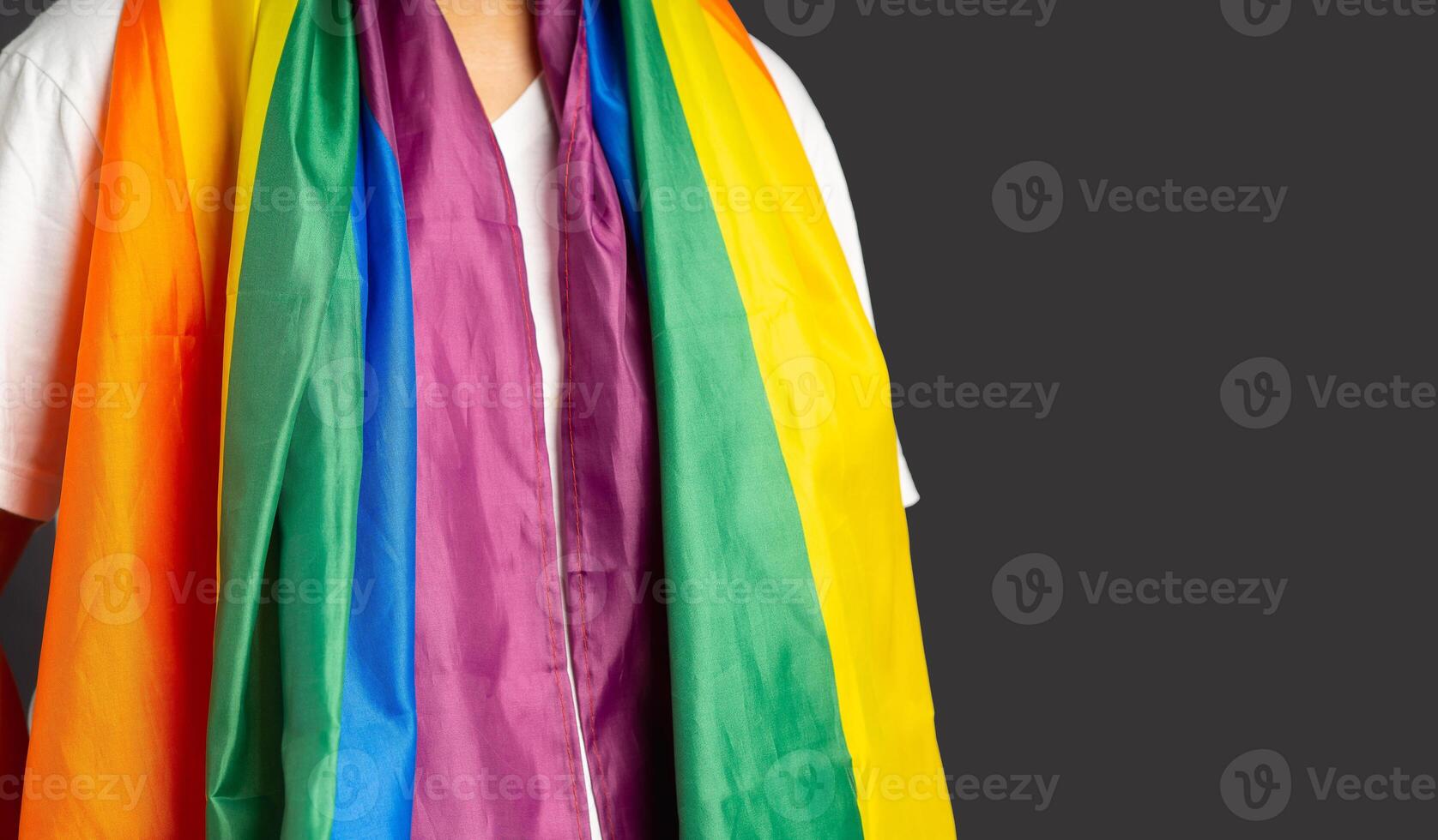 People covering with the rainbow flag or LGBT flag while standing on a gray background photo