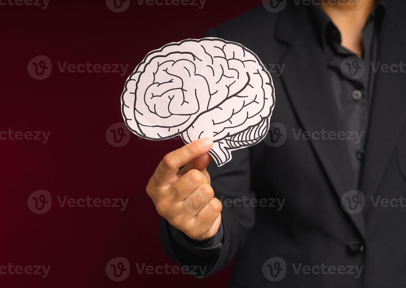 Close-up of hand holding a brain shape made from paper standing on a red background photo