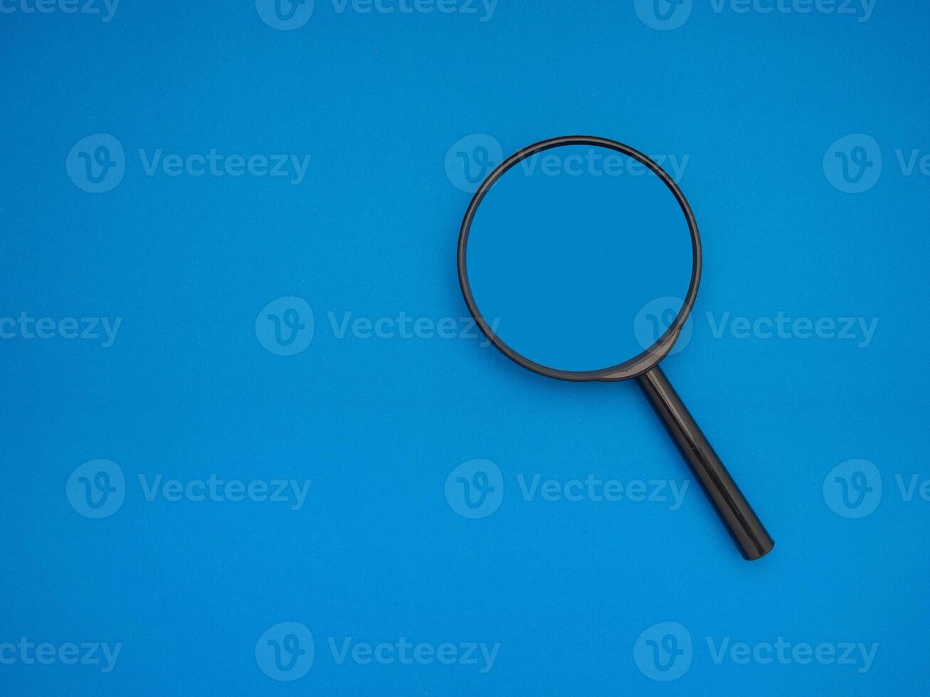 Search concept. A magnifying glass on a blue background with copy space for text photo