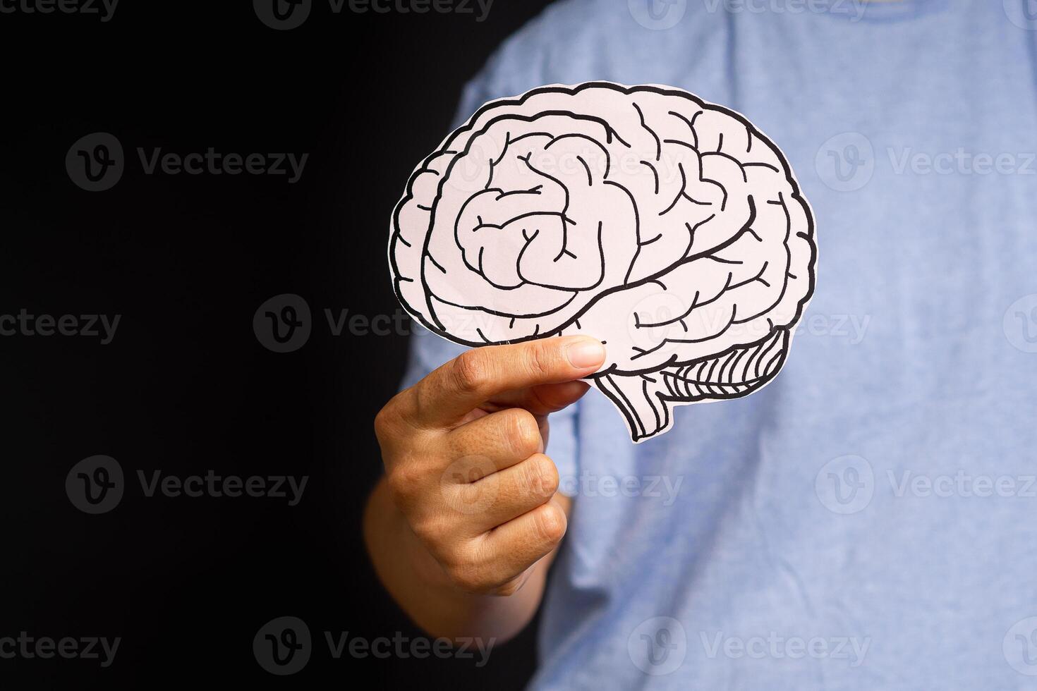 Close-up of hand holding a brain shape made from paper standing on a gray background photo