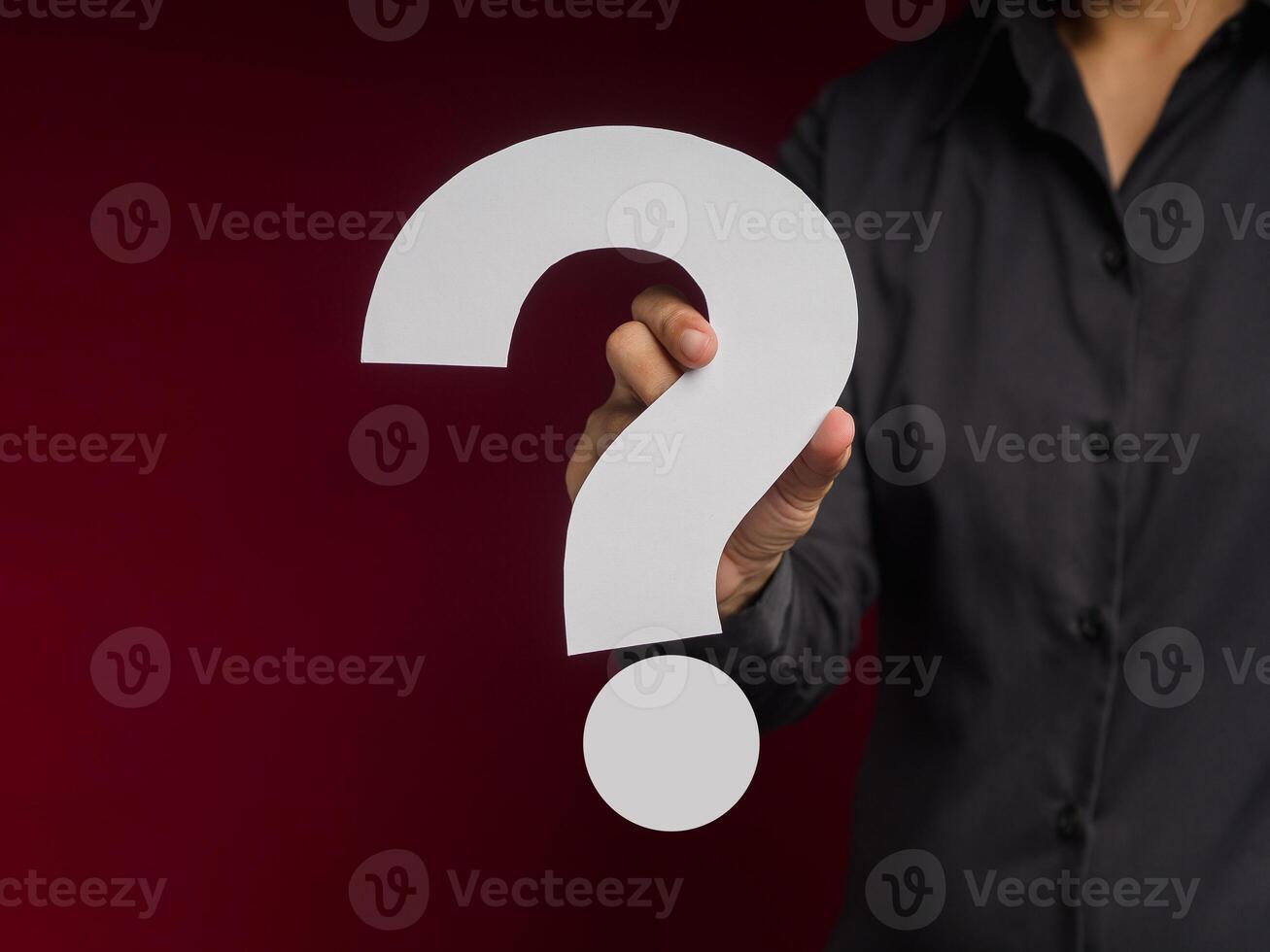 Businessman holding a white question mark paper while standing over a red background photo