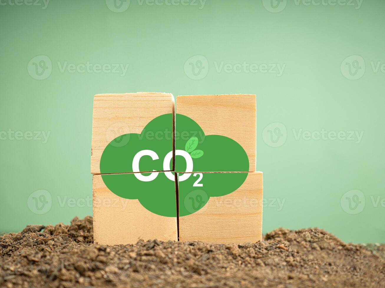 Wooden cubes with CO2 green icons over a soil against a green background photo