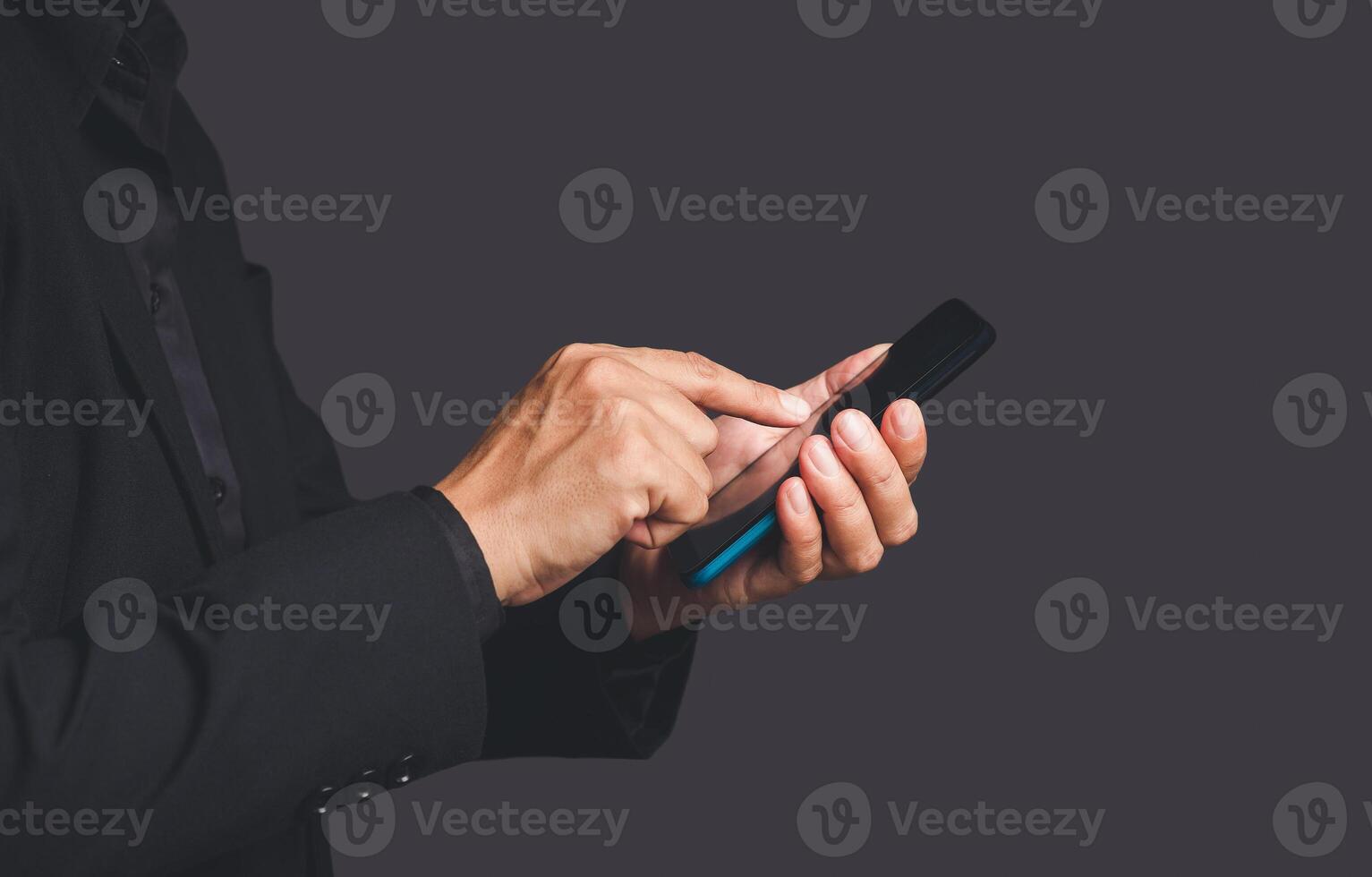 Close-up of hands businessman in a suit using a mobile phone while standing over a gray background photo