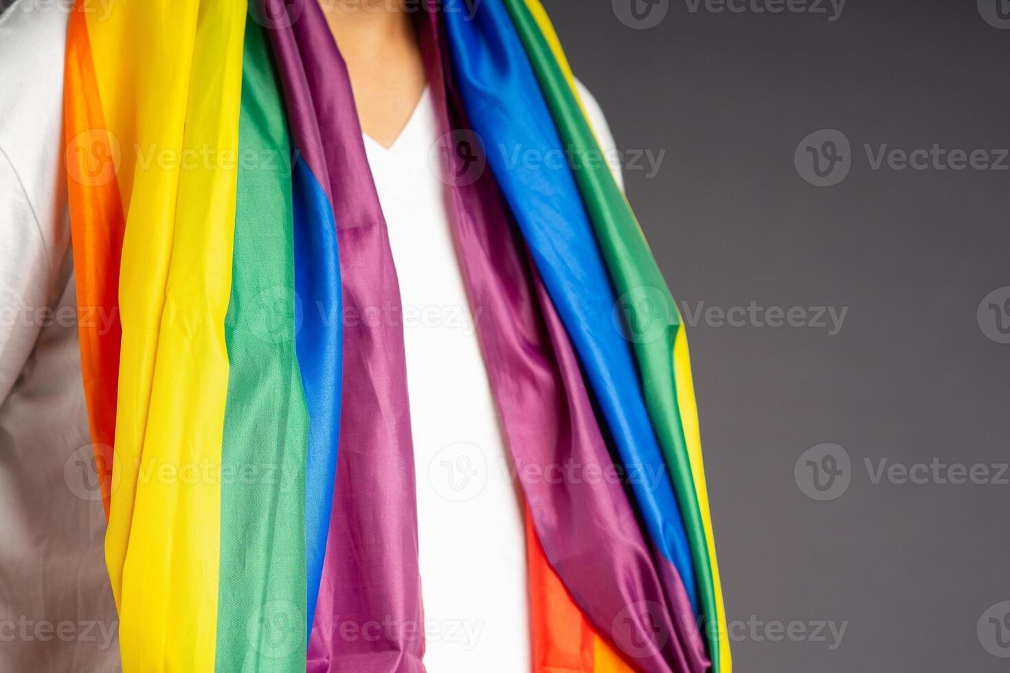 People covering with the rainbow flag or LGBT flag while standing on a gray background photo