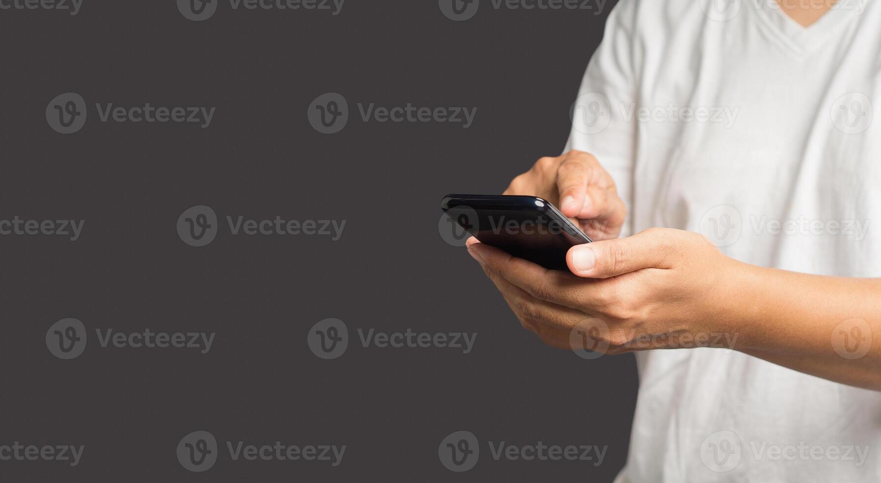 Close-up of hands using a mobile phone while standing over a gray background photo