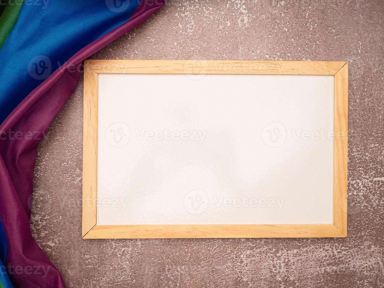 Top view of the rainbow flag or LGBT and a blank mini whiteboard with the wooden border over a cement floor photo