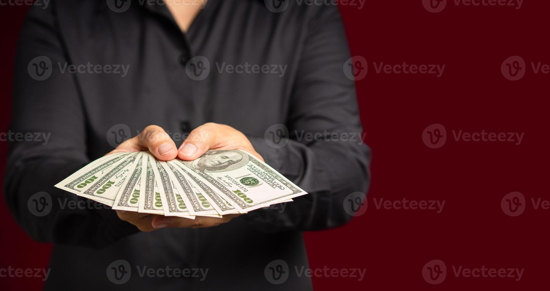 Businessman holding US banknotes on a red background while standing in the studio photo