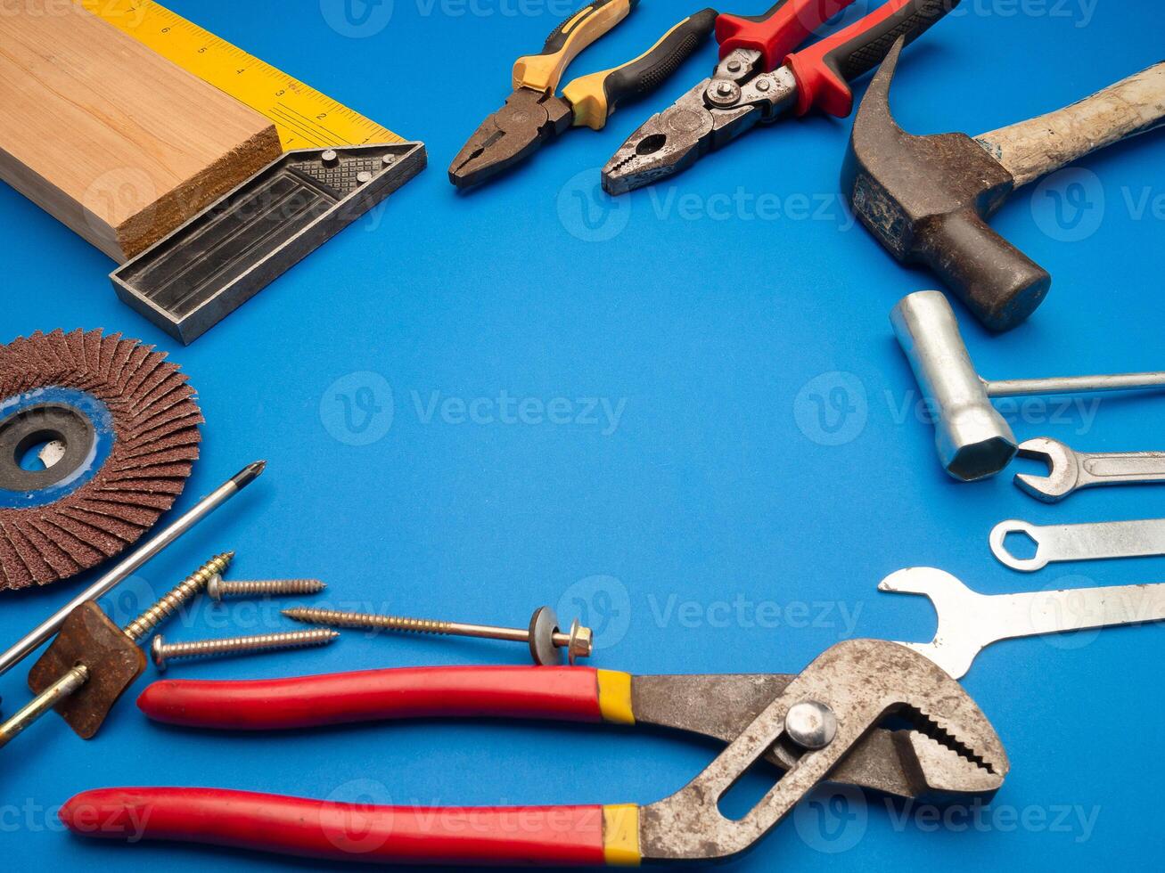 Work tools on a blue background. A hammer, screwdriver, spanner, and pliers photo