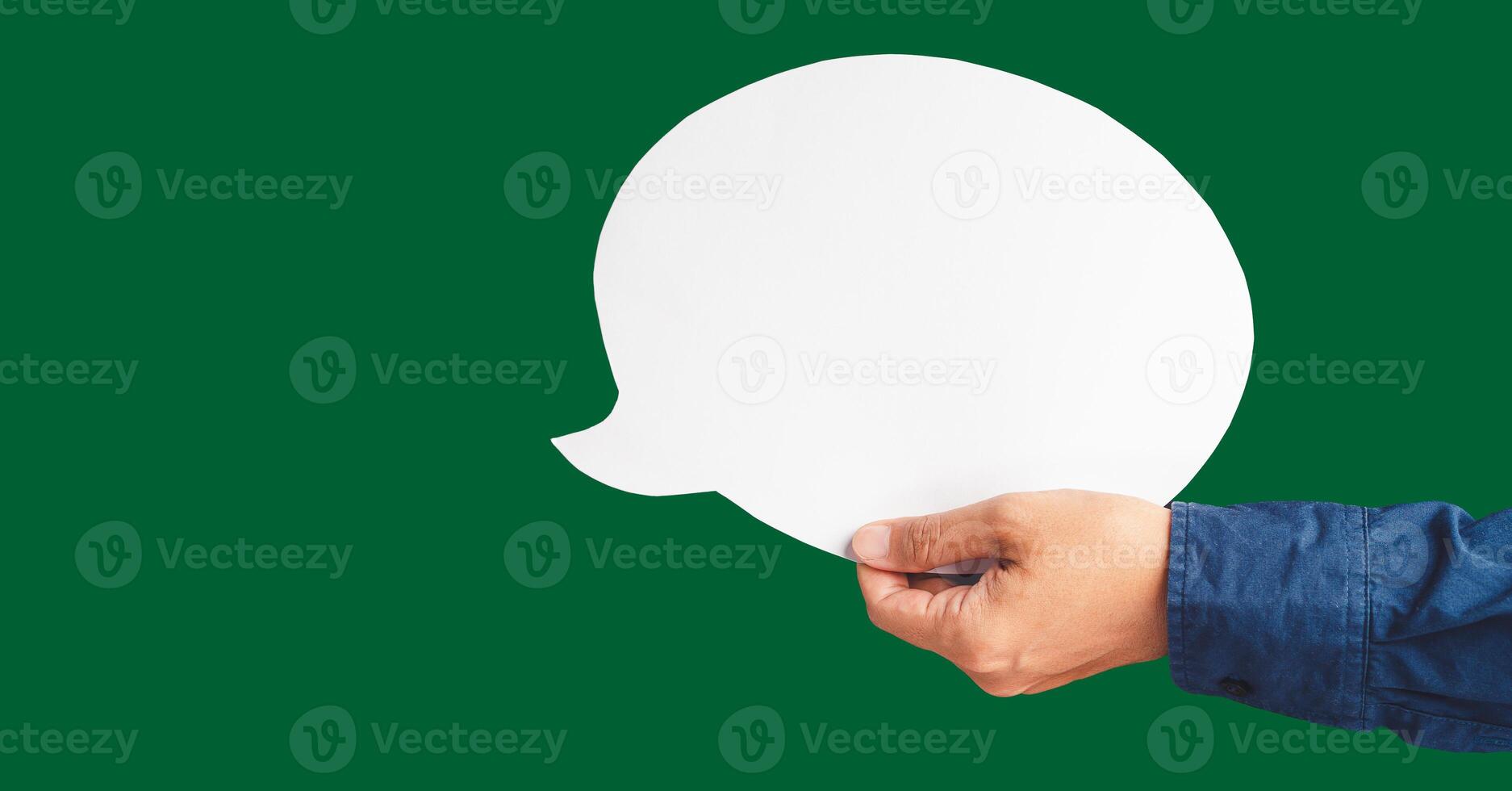 Close-up of hand holding a white speech bubble against a green background photo