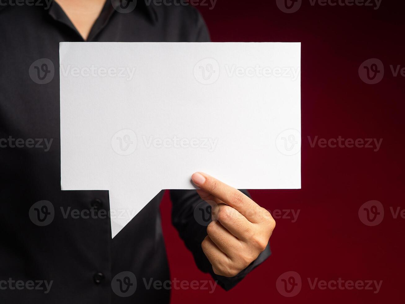 Hand holding a white speech bubble against a red background while standing in the studio photo