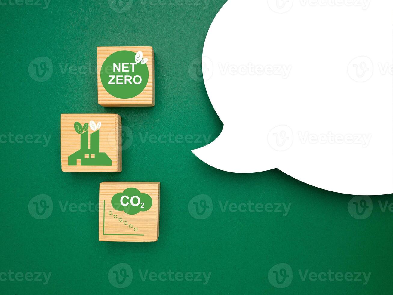 Wooden cubes with CO2 green icons and a blank white speech bubble over a green background photo