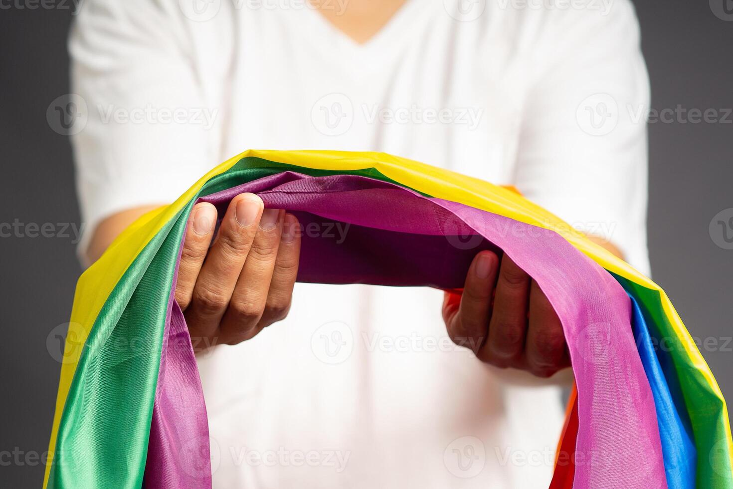 Close-up of hand holding the rainbow flag or LGBT flag while standing on a gray background photo