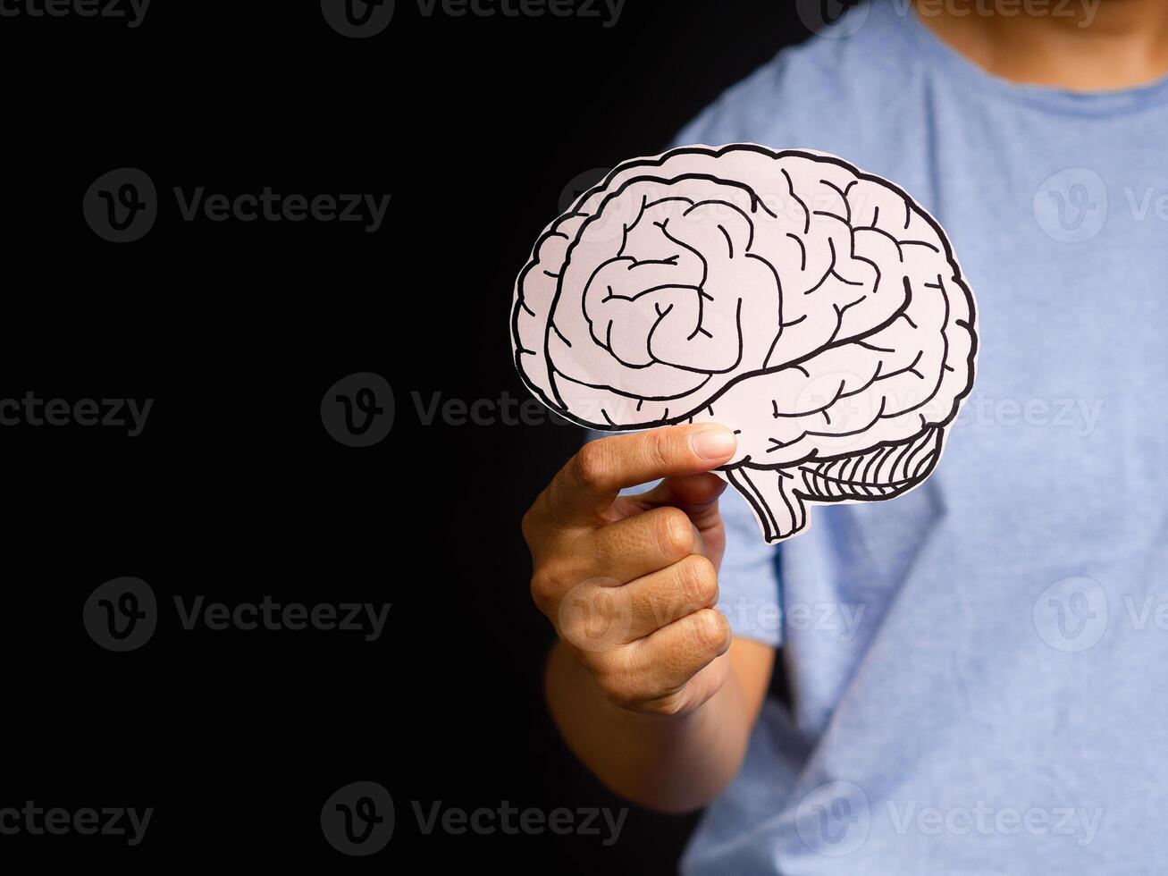 Close-up of hand holding a brain shape made from paper standing on a black background photo
