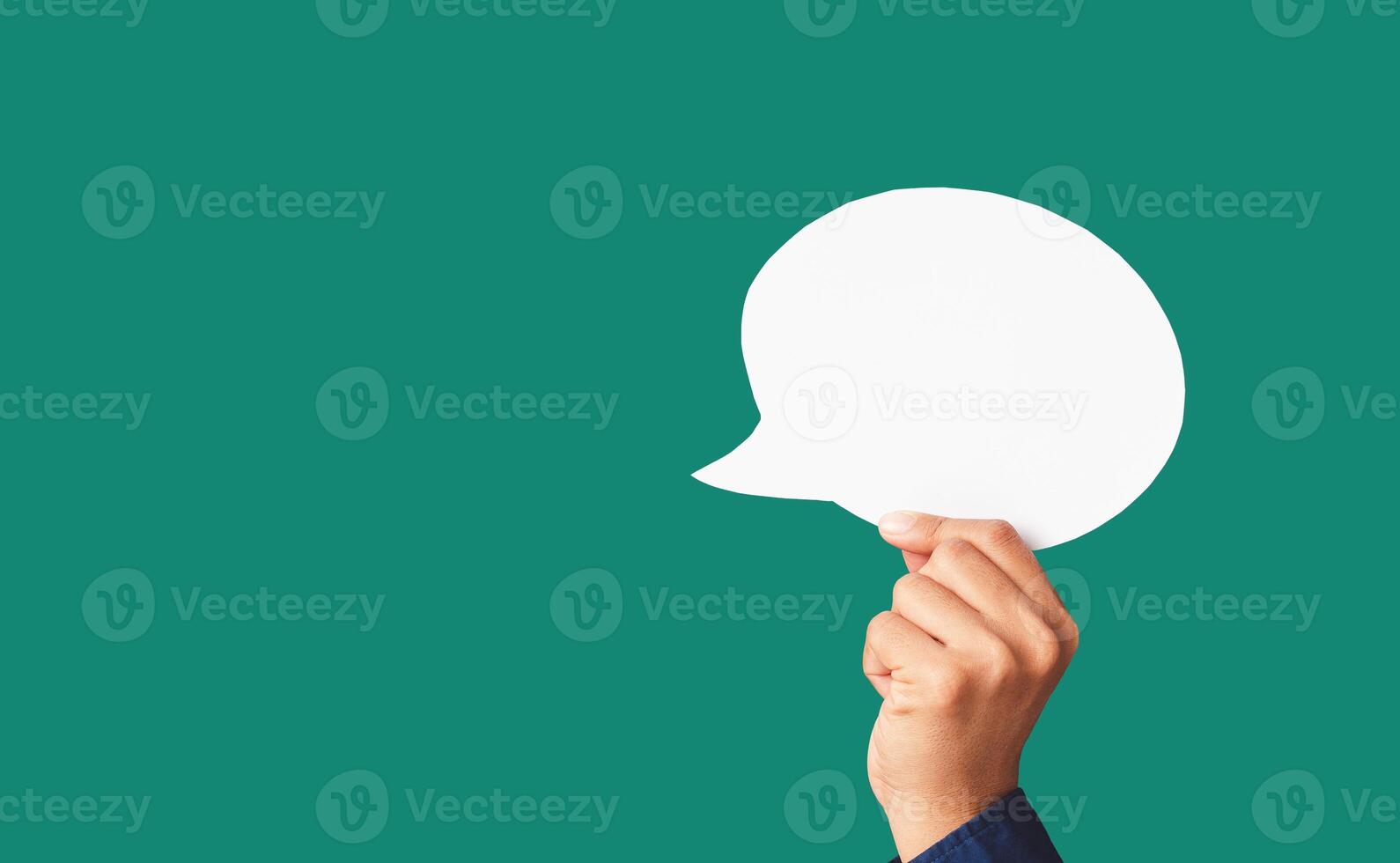 Close-up of hand holding a white speech bubble on a green background photo