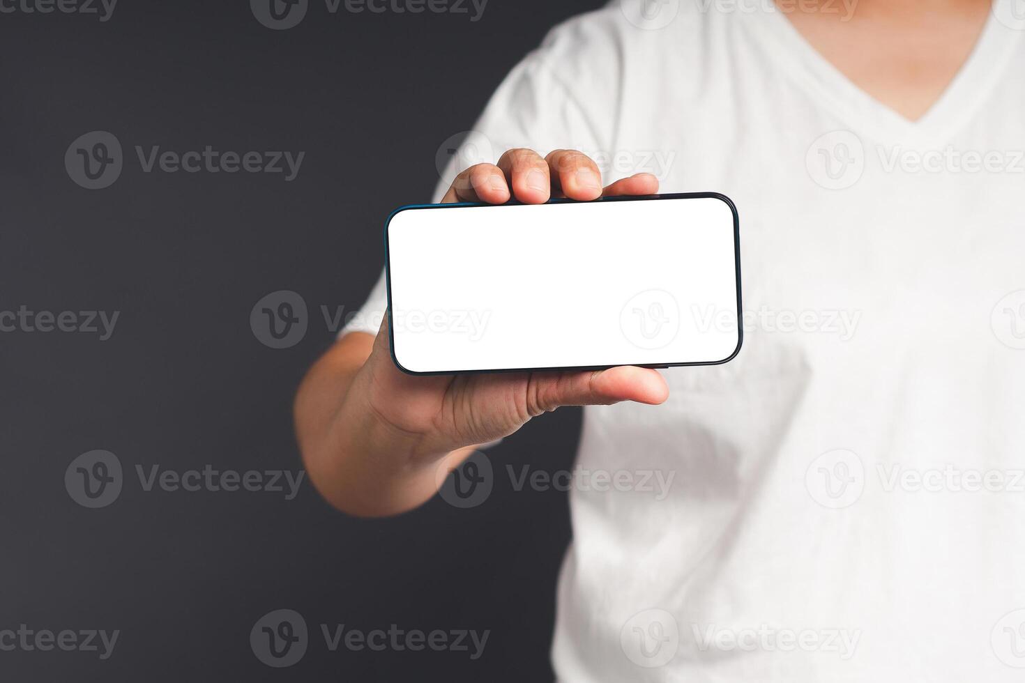 Hand holding a blank screen smartphone while standing on a gray background photo