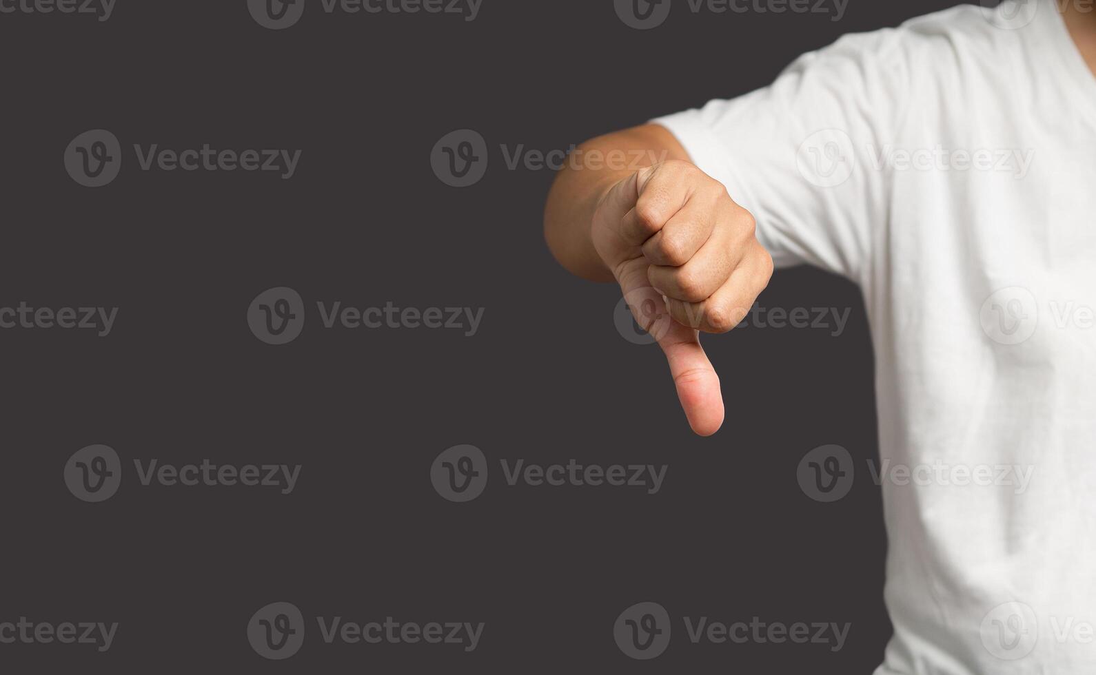 Close-up of man hand showing thumbs down while standing on a gray background. photo