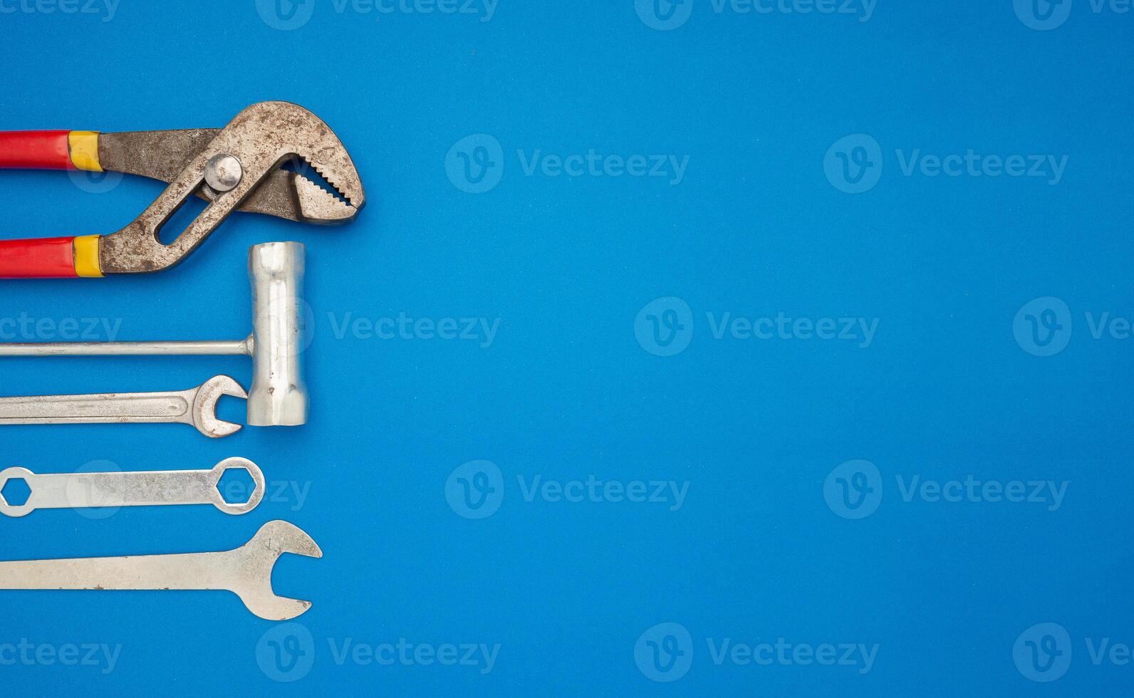 Work tools over a blue background. Pliers, screwdriver, and spanner photo