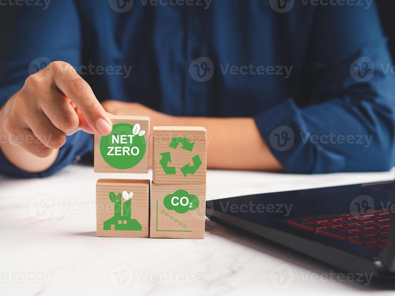 Hand holding a wooden cube with green icons over a marble table while sitting in the office photo