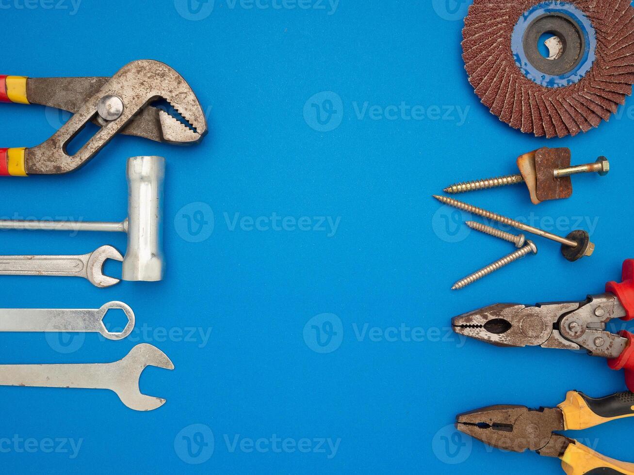 Work tools on a blue background. A hammer, screwdriver, spanner, and pliers photo