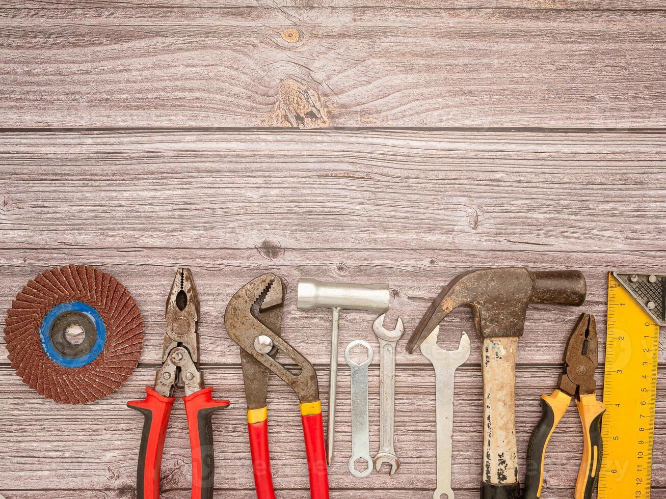 Construction tools, a hammer, screwdriver, screws, and pliers on a wooden table photo