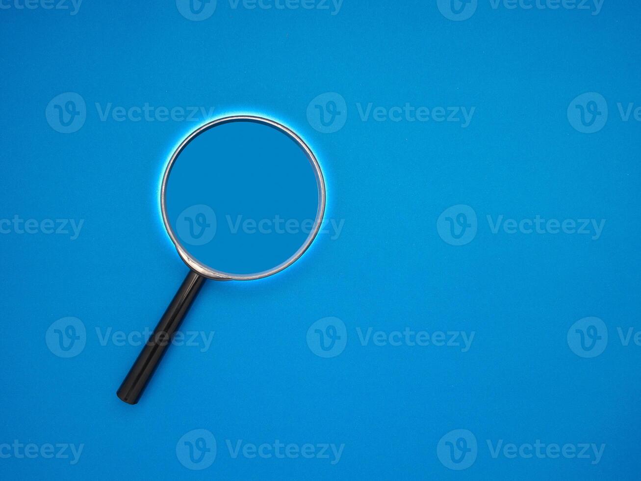 Search concept. A magnifying glass on a blue background with copy space for text photo